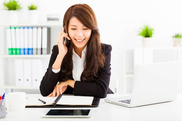 34615594 - happy business woman talking on the phone in office
